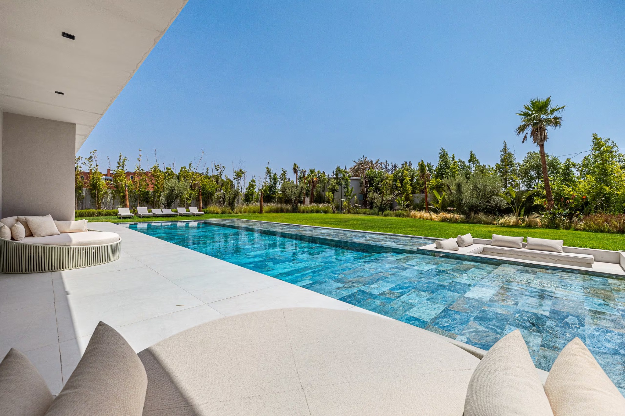 The villa’s shaded terrace overlooking the pool and palm-lined garden