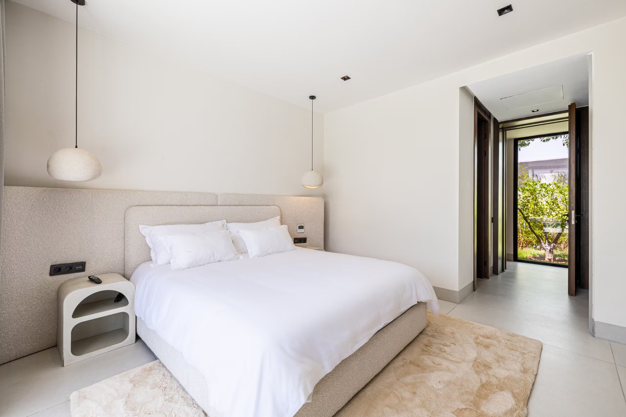 A bright villa bedroom with a double bed and doors opening towards the garden